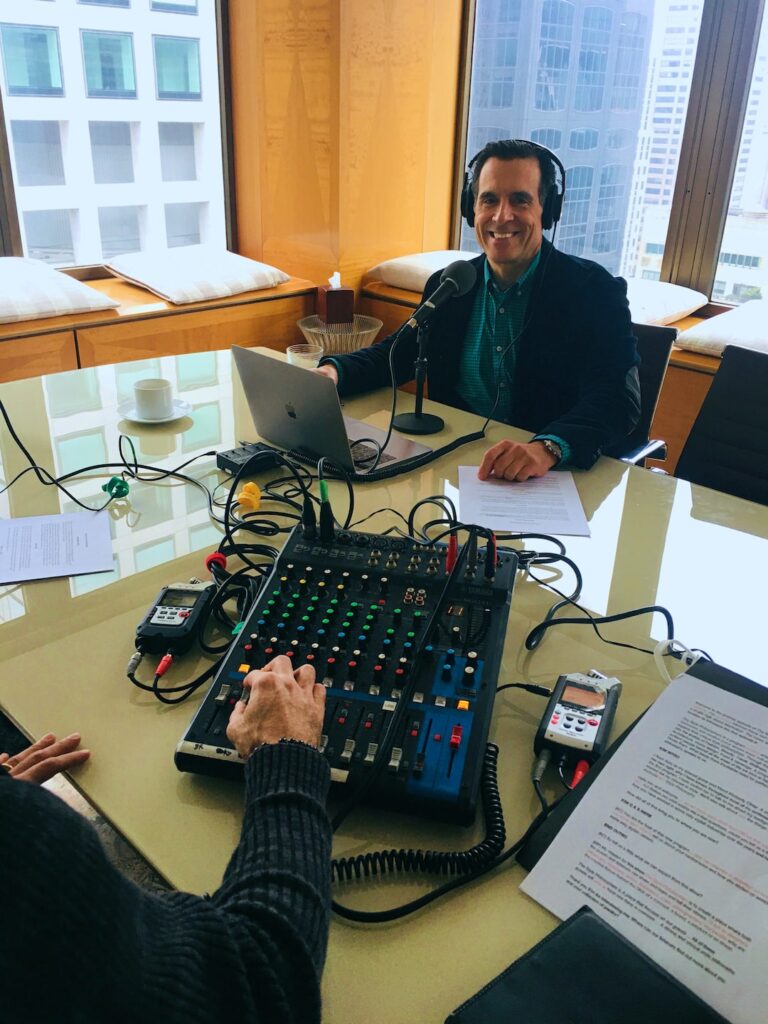 person smiling wearing headphone and in-front of him is an audio mixing device 