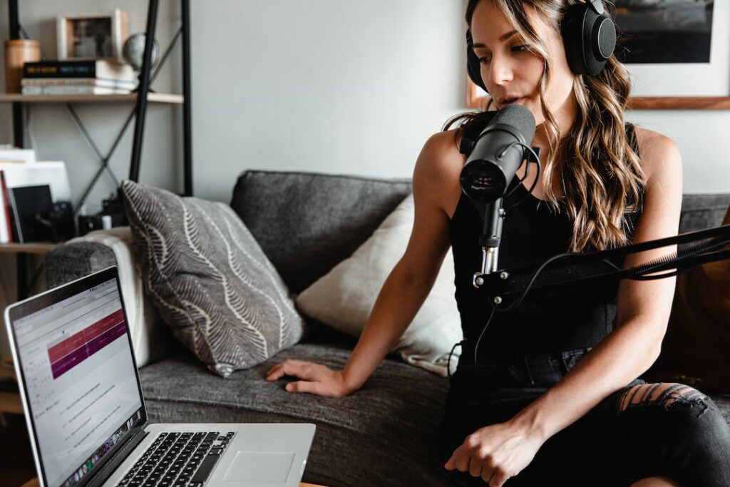 female person singing in a studio mic by looking at her laptop