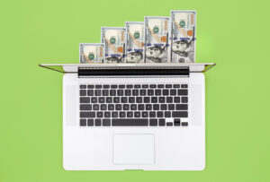 laptop-dollar-bills-color-background-flat-lay