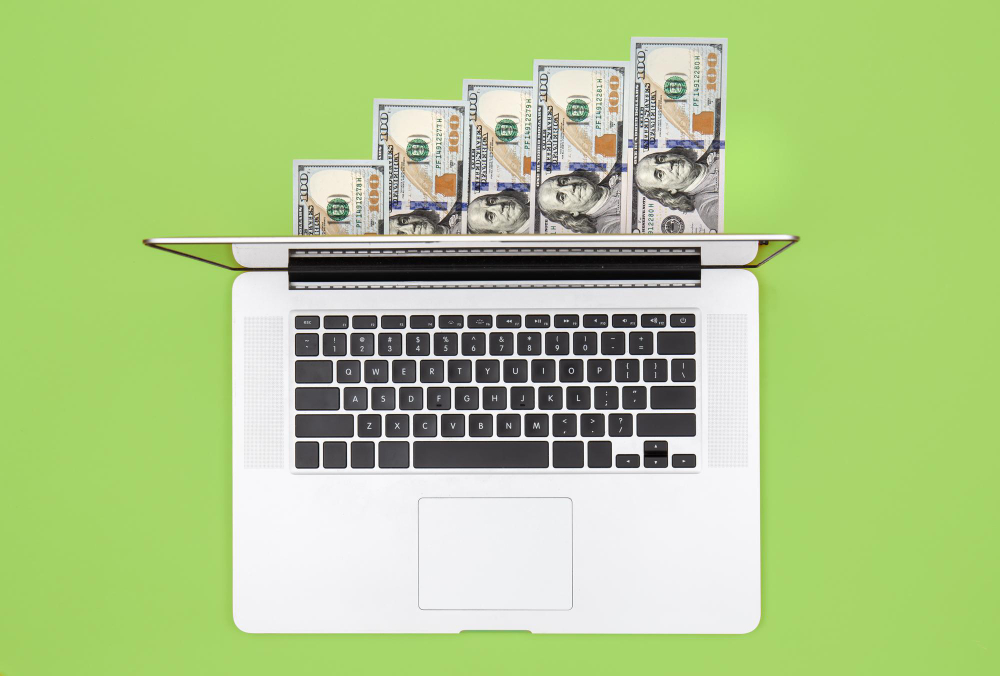 laptop-dollar-bills-color-background-flat-lay
